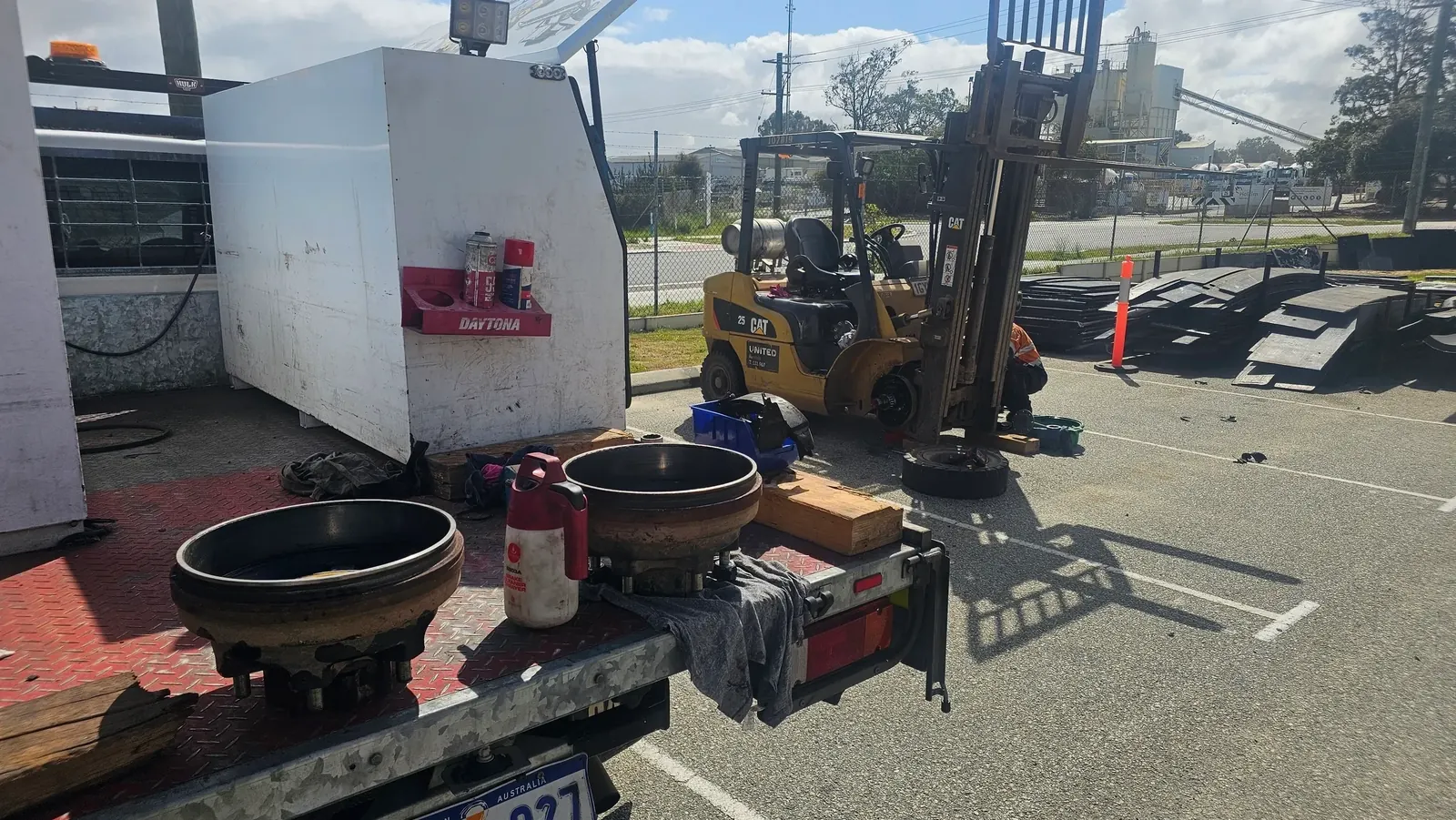 A CAT forklift up on blocks with a wheel off, being worked on in a yard