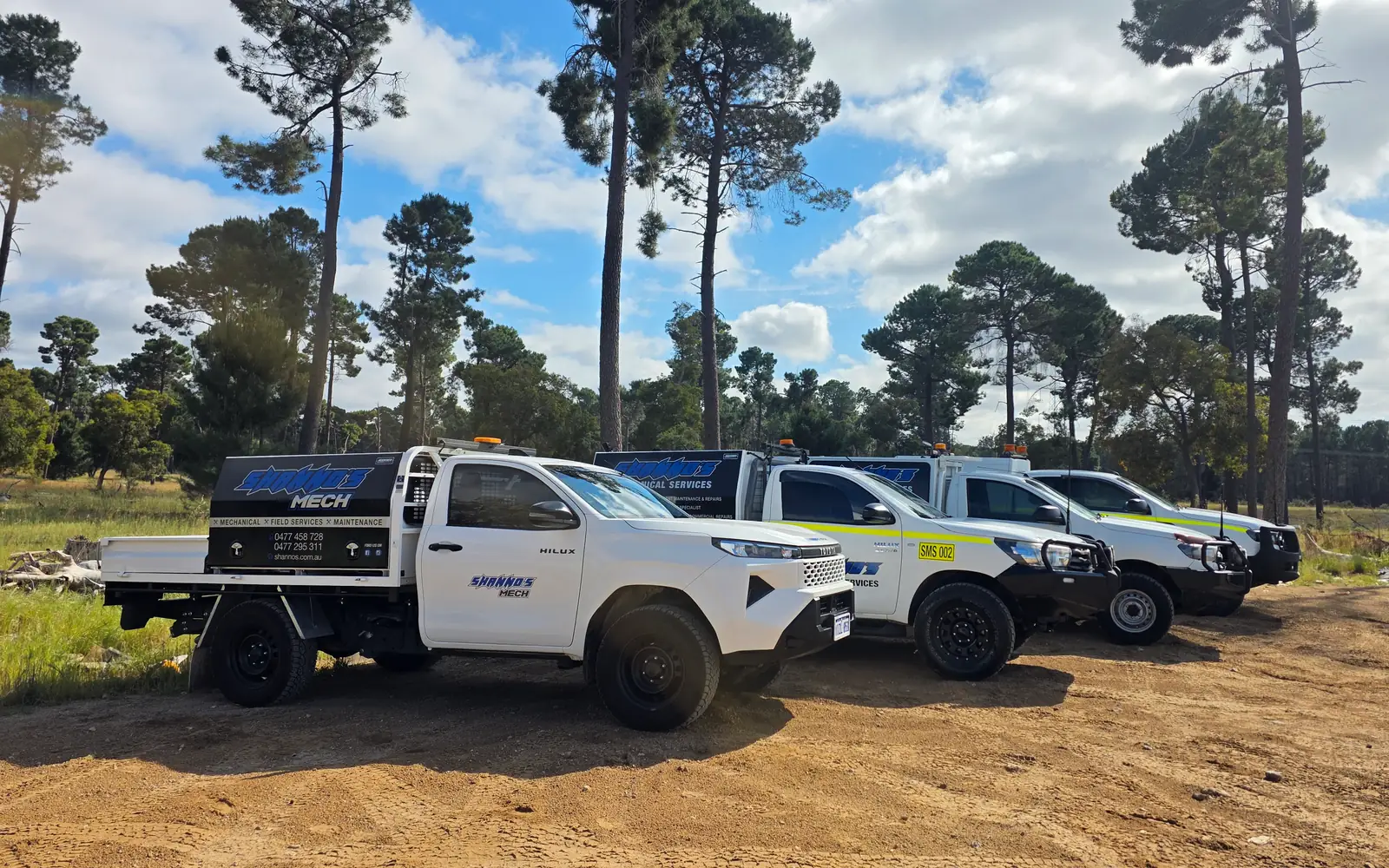 Four Shanno&rsquo;s service utes parked in a row on a dirt clearing among pine trees
