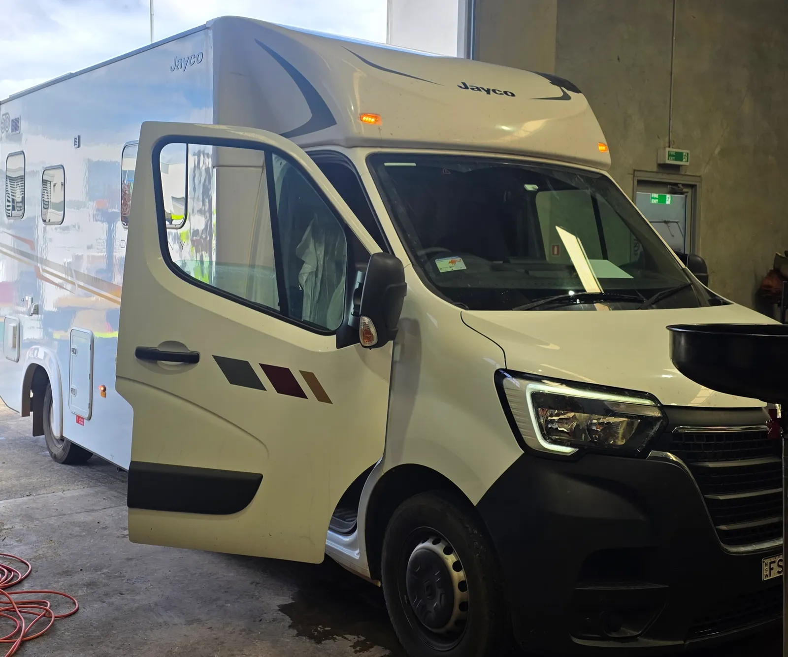 A white Jayco motorhome in the workshop with the cab door open