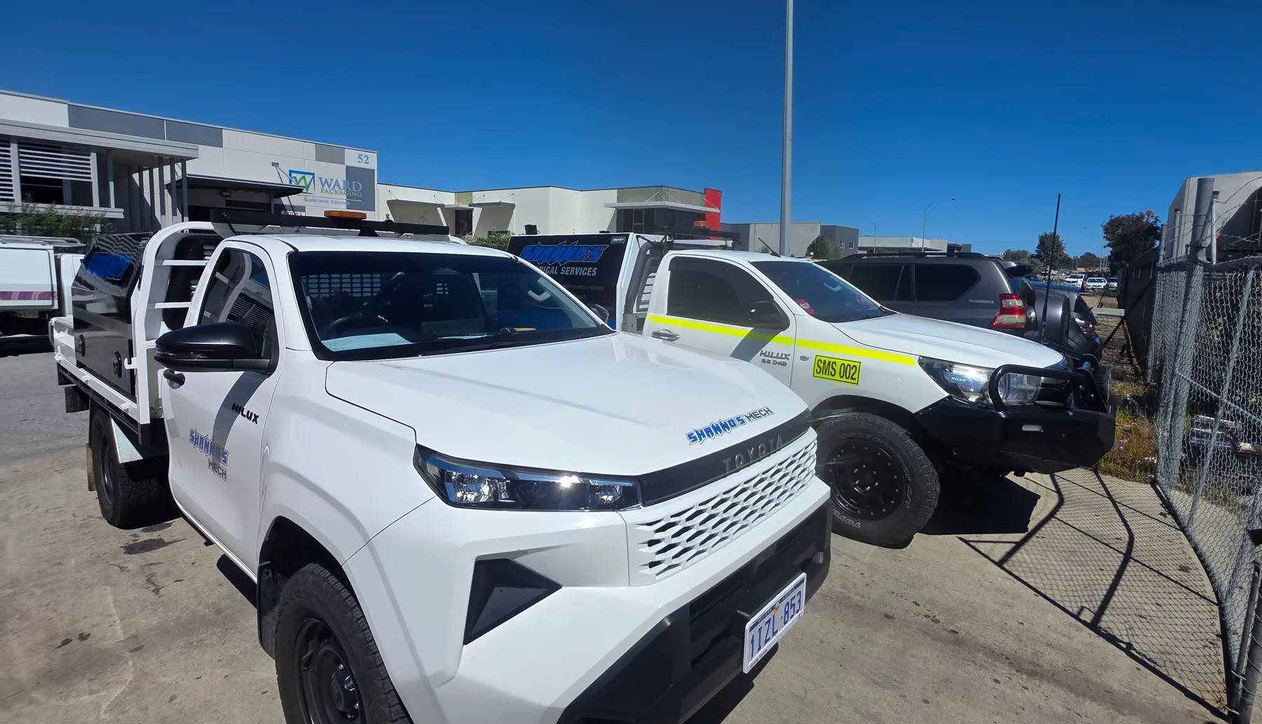 Two white Shanno&rsquo;s Hilux utes parked outside the yard